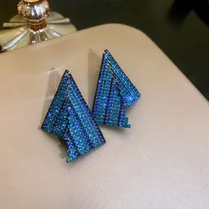 Macro view of geometric silver needle earrings with blue and green rhinestones