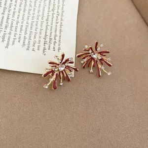 Detail view of red enamel firework-shaped earrings with clear zircon accents