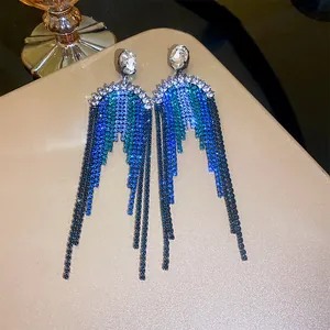 Detail of long tassel earrings featuring gradient blue and green rhinestone chains.
