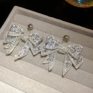 Macro view of sparkly bow-shaped earrings encrusted with clear cubic zirconia stones.