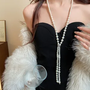Detail showing a long French luxury tassel pearl necklace on a model wearing fur coat