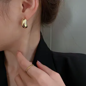 Detailed close-up view of elegant polished gold bean-shaped earrings on a model