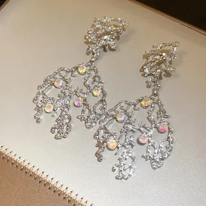 Detailed view of irregular silver-tone dangle earrings with round iridescent crystals