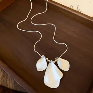 Detailed close-up of minimalist necklace with three matte white irregular petal pendants