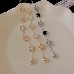 Gold and silver plated flower charm bracelets with pearly petals on a ceramic plate