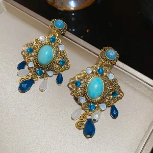 Close-up of vintage gold filigree earrings with blue stones and teardrop pendants.