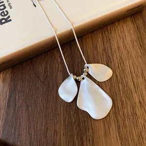 Macro detail of matte white irregular wrinkled petal pendants on a silver chain necklace