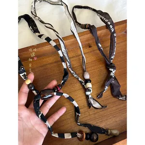 Handmade ethnic style fabric and wooden bead necklaces on a wooden tray.