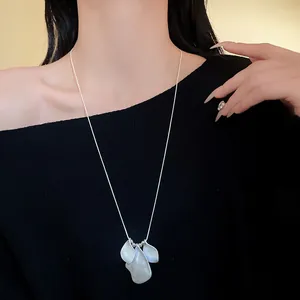 Close-up of minimalist silver necklace with irregular petal pendants on model.