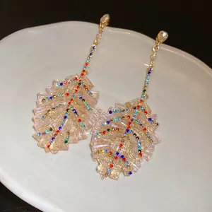 Macro detail of elegant leaf-shaped drop earrings with colorful sparkling rhinestones.