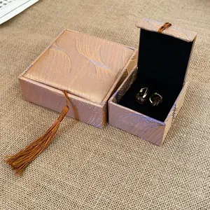 Close-up of silk jewelry box with elegant feather pattern and decorative tassel.