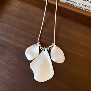 Detail of minimalist necklace featuring irregular white petal pendants on silver chain