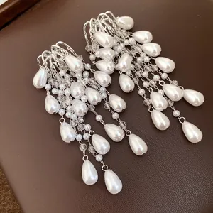 Close-up of elegant long tassel earrings with white teardrop pearls and clear crystals