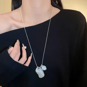 Elegant minimalist irregular pleated petal necklace detail on black off-shoulder sweater