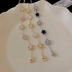 Detailed view of elegant gold and silver plated clover flower bracelets on a cream plate