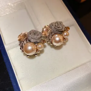 Close-up of elegant champagne pearl and mesh rose flower stud earrings in box