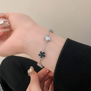 Elegant silver-plated bracelet with black and white clover charms shown on a wrist.
