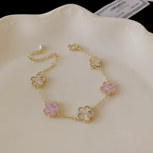 Macro detail of elegant gold plated five-flower bracelet with pink and white shell petals