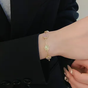 Detail view of a gold plated flower bracelet worn on a wrist against a dark blazer