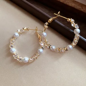 Elegant gold hoop earrings featuring alternating sparkling zircons and white pearls.