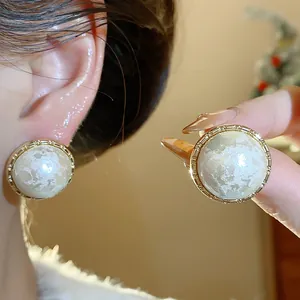 Primer plano de pendientes redondos bañados en oro con textura de perla de algodón