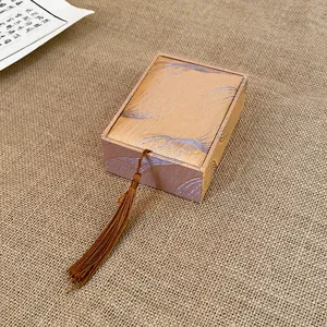 Close-up of elegant bronze jewelry box with silk tassel and feather pattern fabric