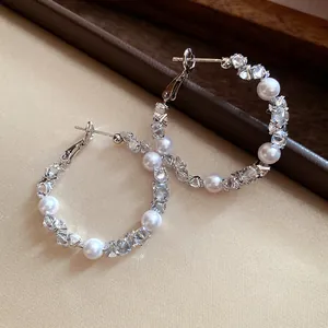Close-up of silver hoop earrings featuring sparkling cubic zirconia and white pearls.