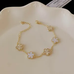 Detail view of gold-plated bracelet featuring white and gold flower charms