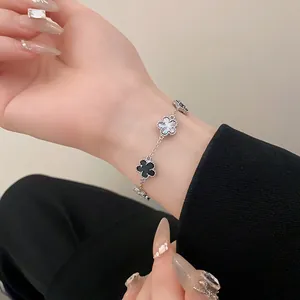 Elegant silver-tone clover bracelet with black and white flower motifs on a woman's wrist
