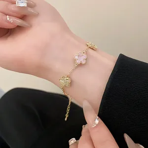Detail of elegant gold-plated bracelet with pink and gold flower charms on wrist