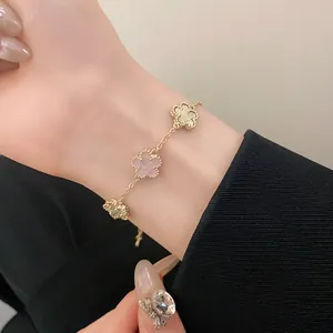 Elegant gold-plated bracelet with pink and textured clover motifs shown on wrist