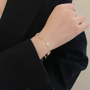 Detailed view of elegant gold plated clover flower bracelet on a model's wrist