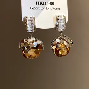 Detail view of amber gemstone earrings with sparkling zircon accents and gold-toned finish