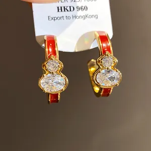 Gold-toned gourd-shaped hoop earrings with red enamel and sparkling cubic zirconia stones.