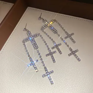 Detail of sparkling zircon cross drop earrings with silver finish in luxury jewelry box