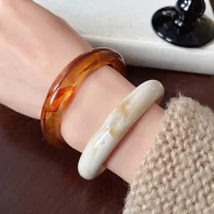 Set of retro irregular resin bangles with amber and marbled textures worn on a wrist
