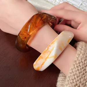 Irregular resin bangles in amber and marbled orange for a vintage minimalist look