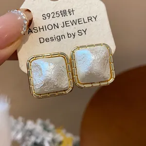 Pendientes de botón cuadrados chapados en oro con incrustación blanca texturizada y plata.