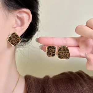 Close-up of retro leopard print flocked earrings with gold metal borders on ears