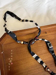 Close-up of bohemian fabric and wooden beaded necklace displayed on a wooden tray
