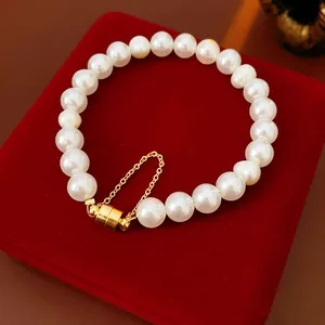 Vue détaillée d'un élégant bracelet en perles blanches avec fermoir magnétique doré et chaîne