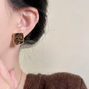 Close-up of vintage square stud earrings with flocked leopard print and gold frame