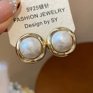Vista detallada de pendientes de botón circulares bañados en oro con perlas de algodón con textura