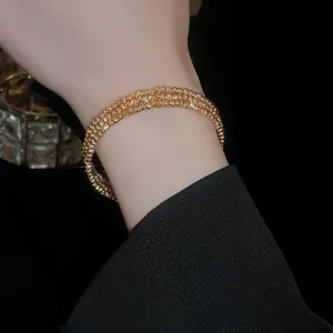 Elegante bracciale multistrato in oro con perle metalliche irregolari su un polso femminile