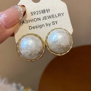 Primer plano de elegantes pendientes de perla de algodón redondos bañados en oro con plata S925