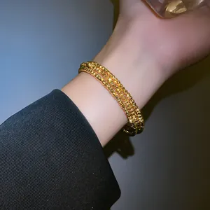 Elegante bracciale a tre strati in grani di metallo dorato con una trama irregolare