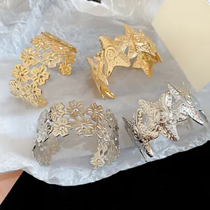 Detail view of stylish metallic wrinkled star and floral cuff bracelets in gold and silver.