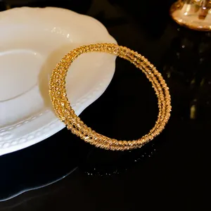 Dettaglio ravvicinato di un elegante bracciale multistrato dorato con finitura a grana metallica