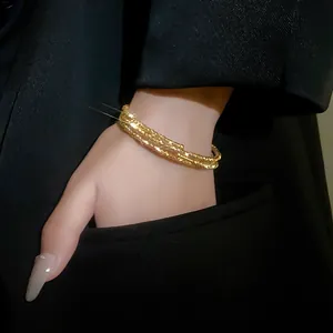 Primo piano di un bracciale dorato multistrato strutturato su un polso elegante.