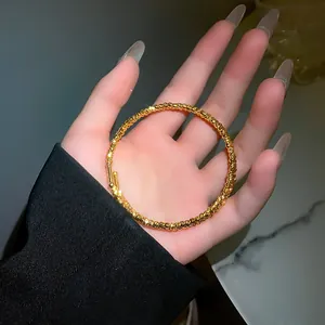 Primo piano di un elegante bracciale dorato con trama granulare irregolare in mano.